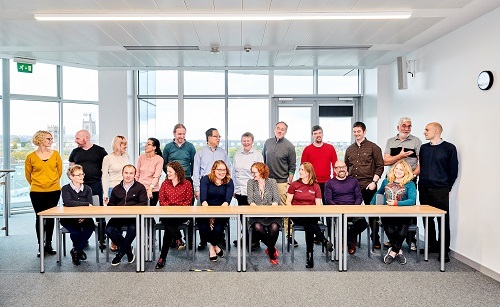 TDepartment staff sitting and standing around a table for a group photo