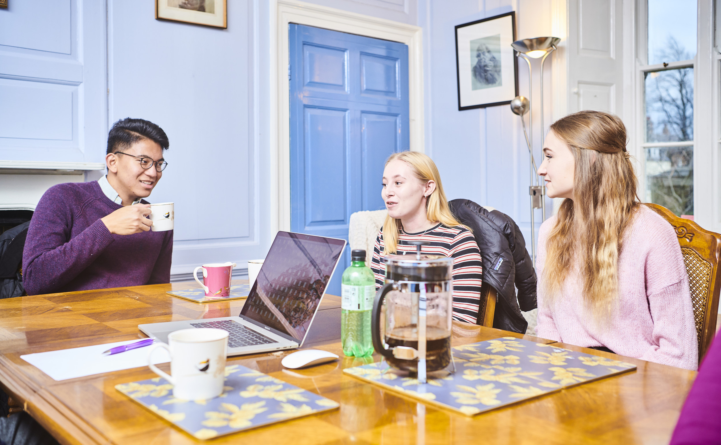 Students having a hot drink and chatting round a table