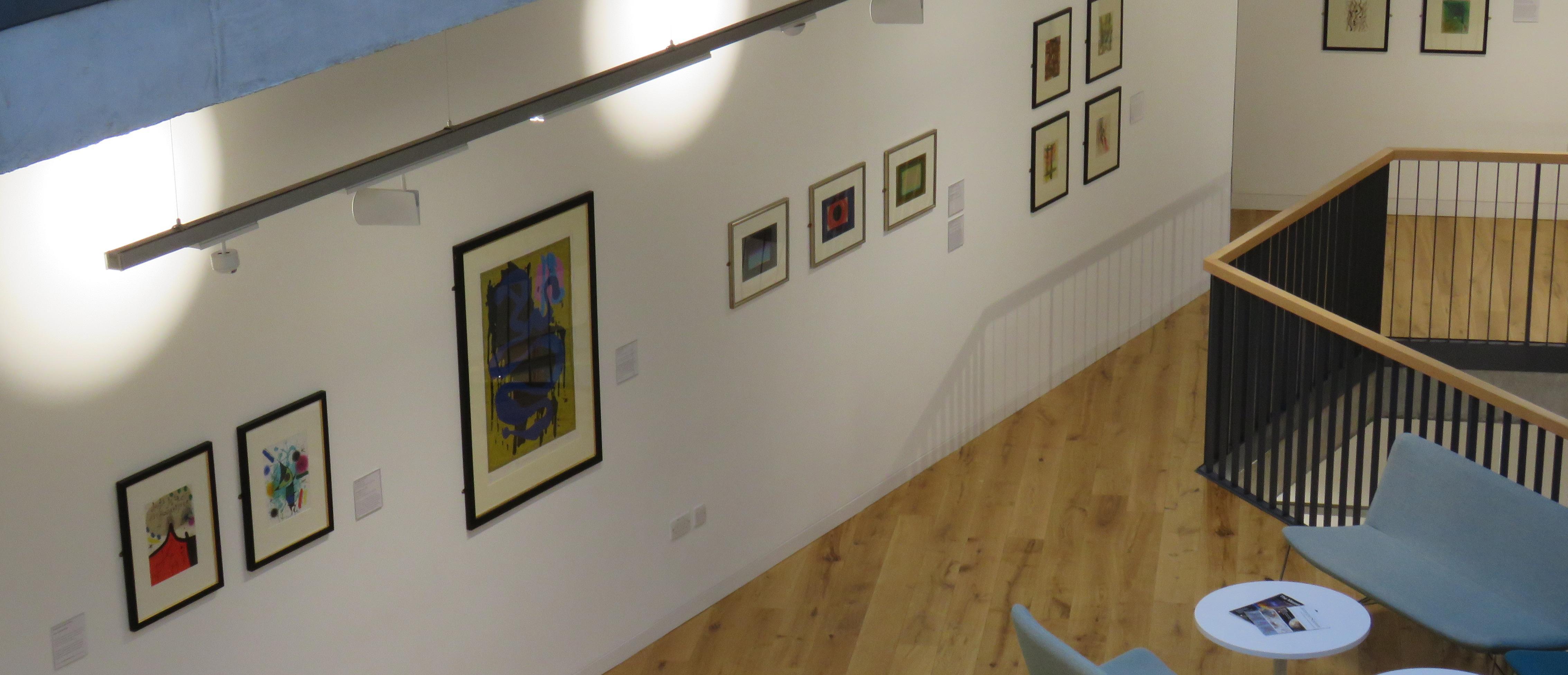 Ten artworks are displayed on a white wall, photographed from above.