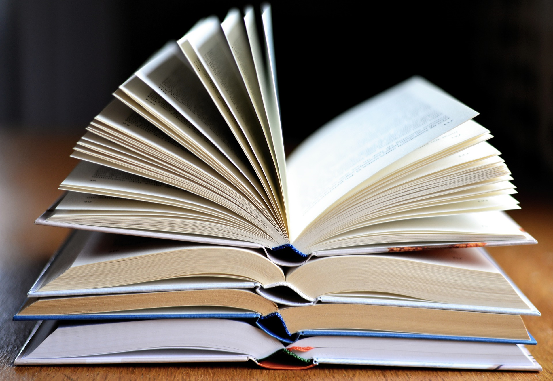 Four open books piled on top of each other