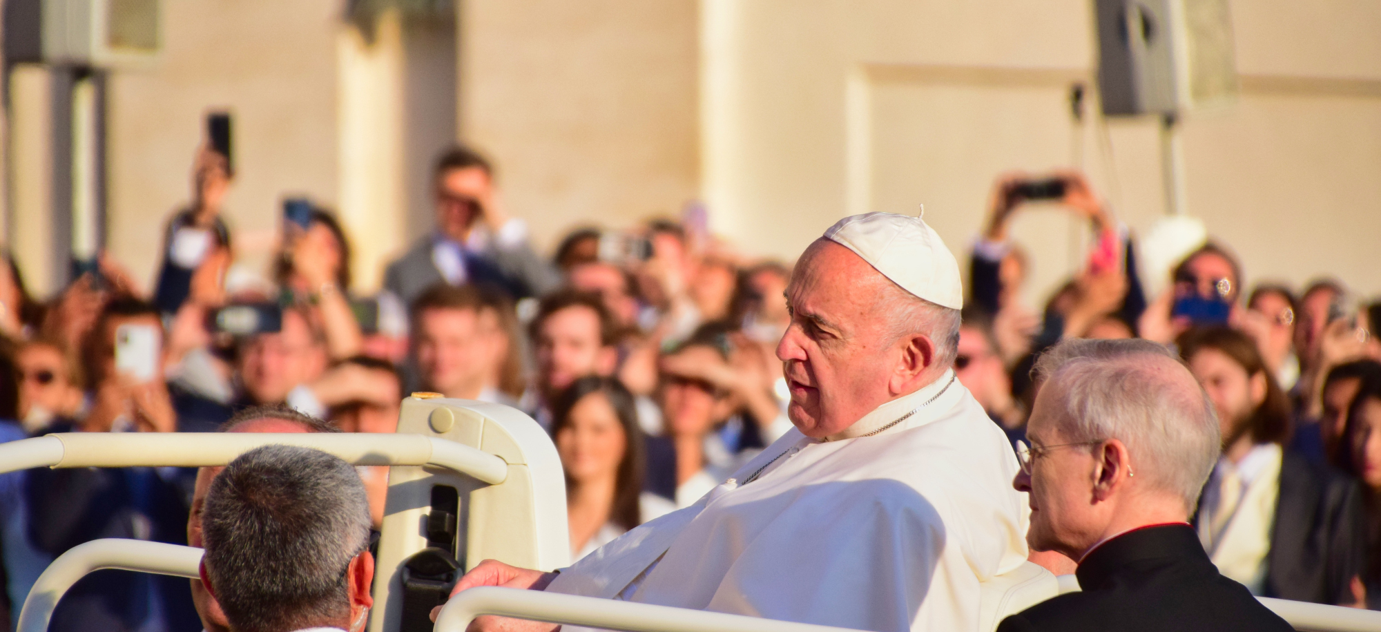 Pope Francis on board some transport while a crowd watches