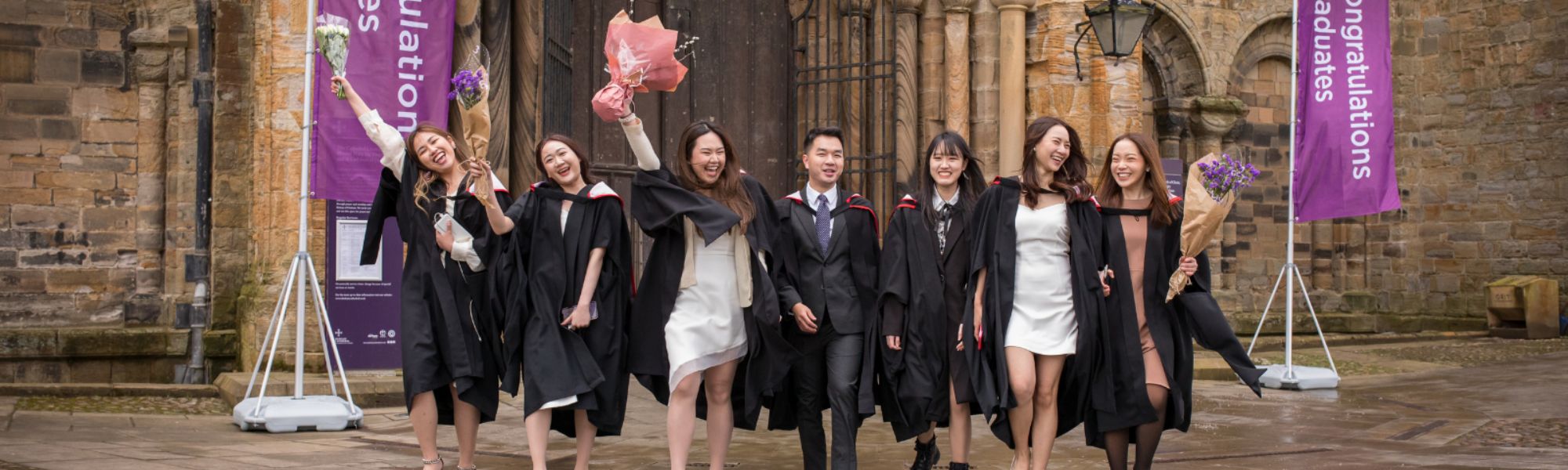 Graduates in robes celebrating in front of Durham Cathedral