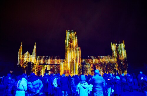 A group of people facing an illuminated cathedral building