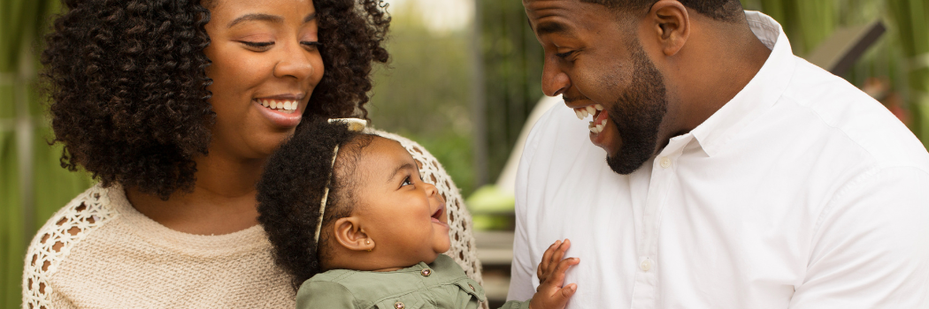 An image of two parents interacting with a young child