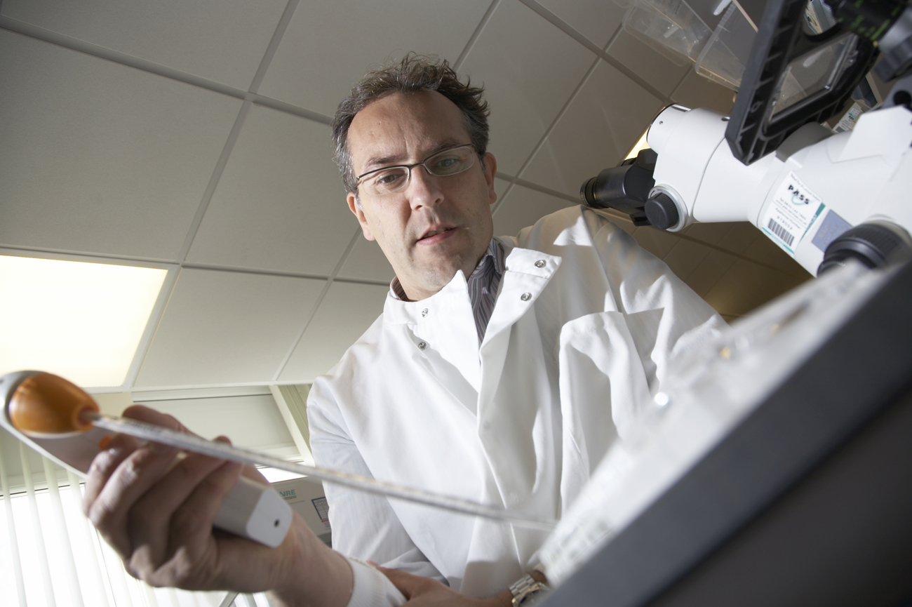 Scientist in lab coat using a pipette