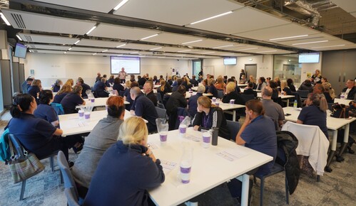 A large number of Durham staff sitting round tables in a large meeting room