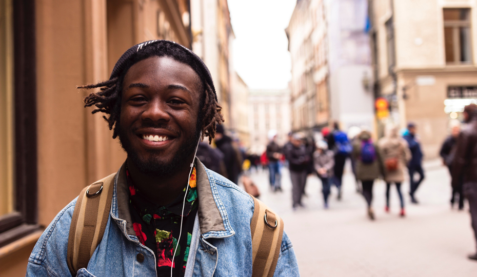 A smiling student walking along a busy street