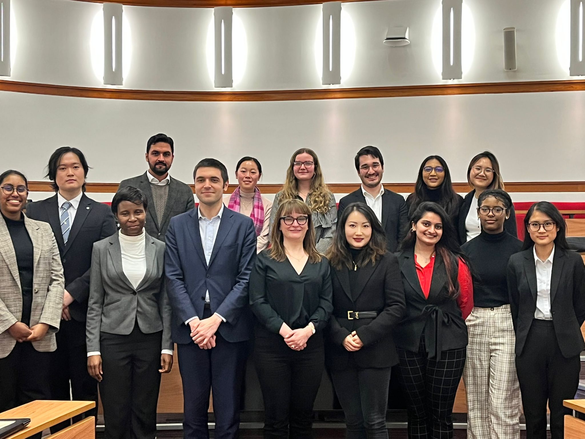 Staff and Students standing in two rows in a lecture room