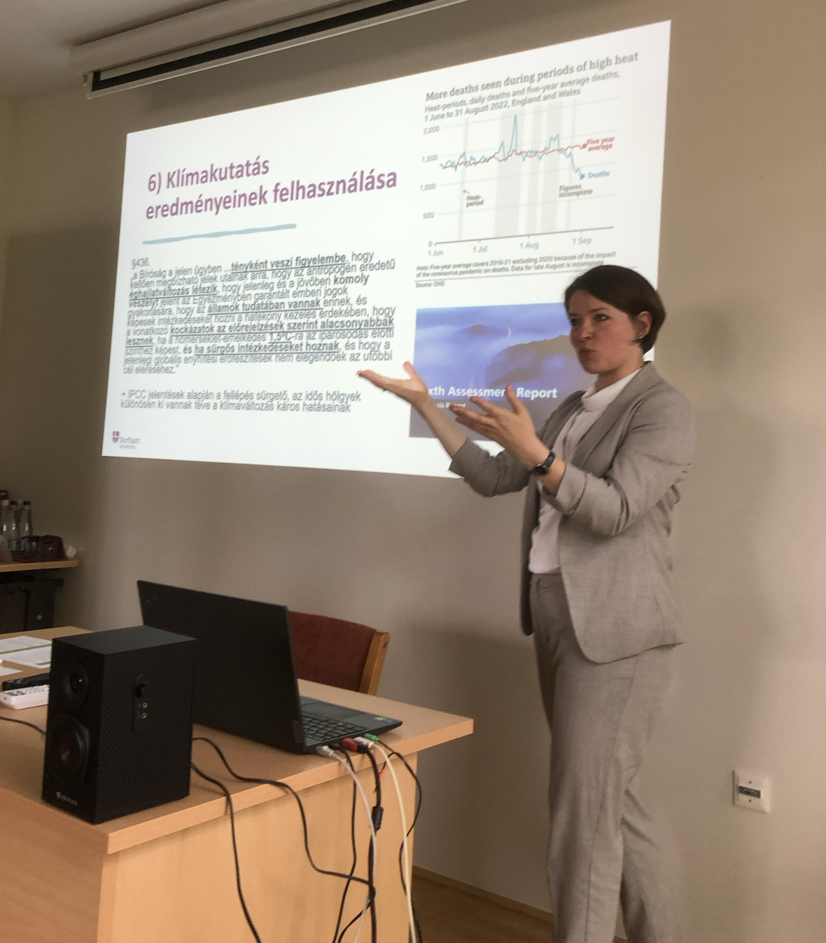 A lady in grey suit teaching in front of a slide show