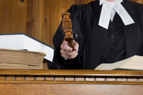 Judge In Traditional Court Robes Using the Gavel