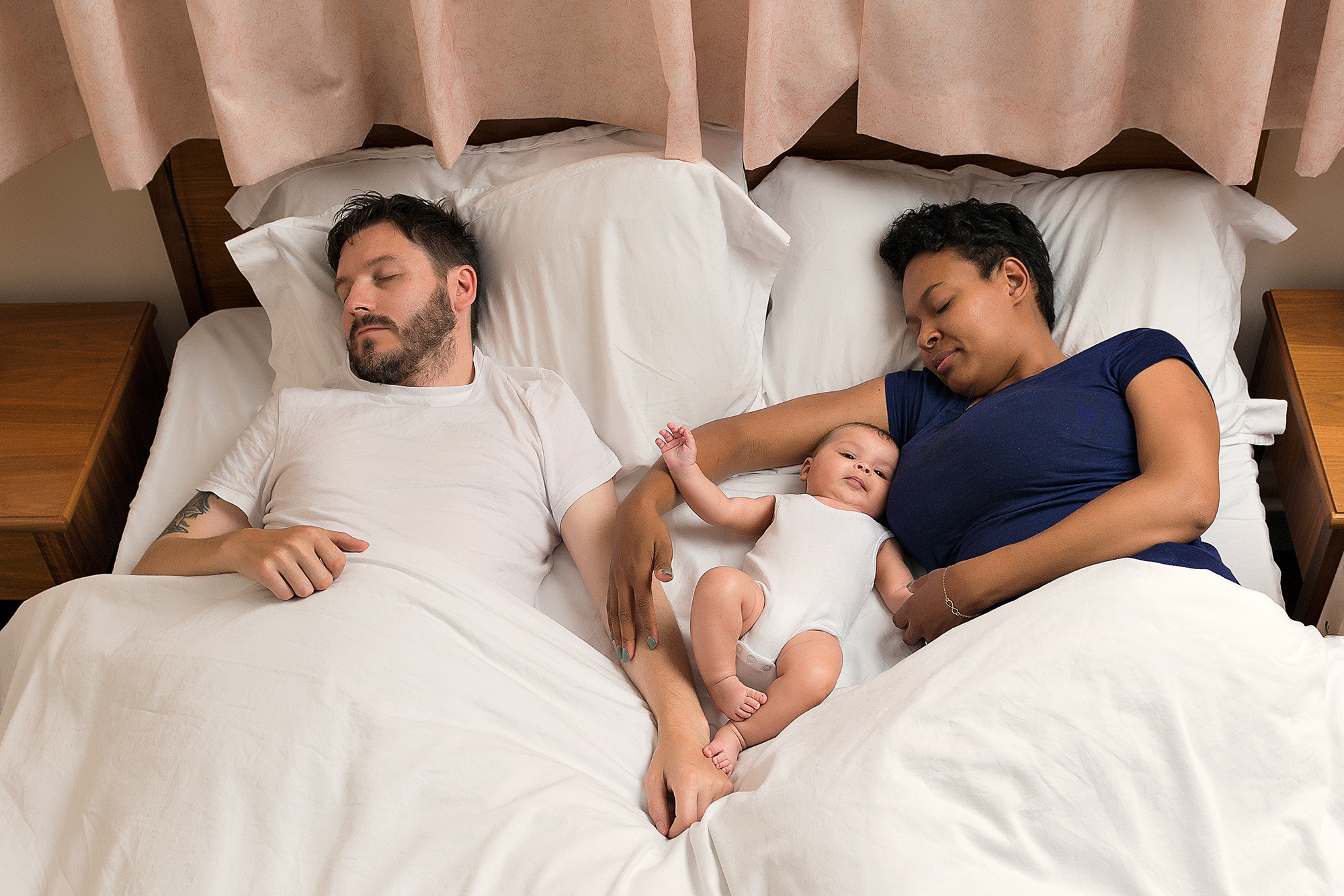Couple laid in bed with baby