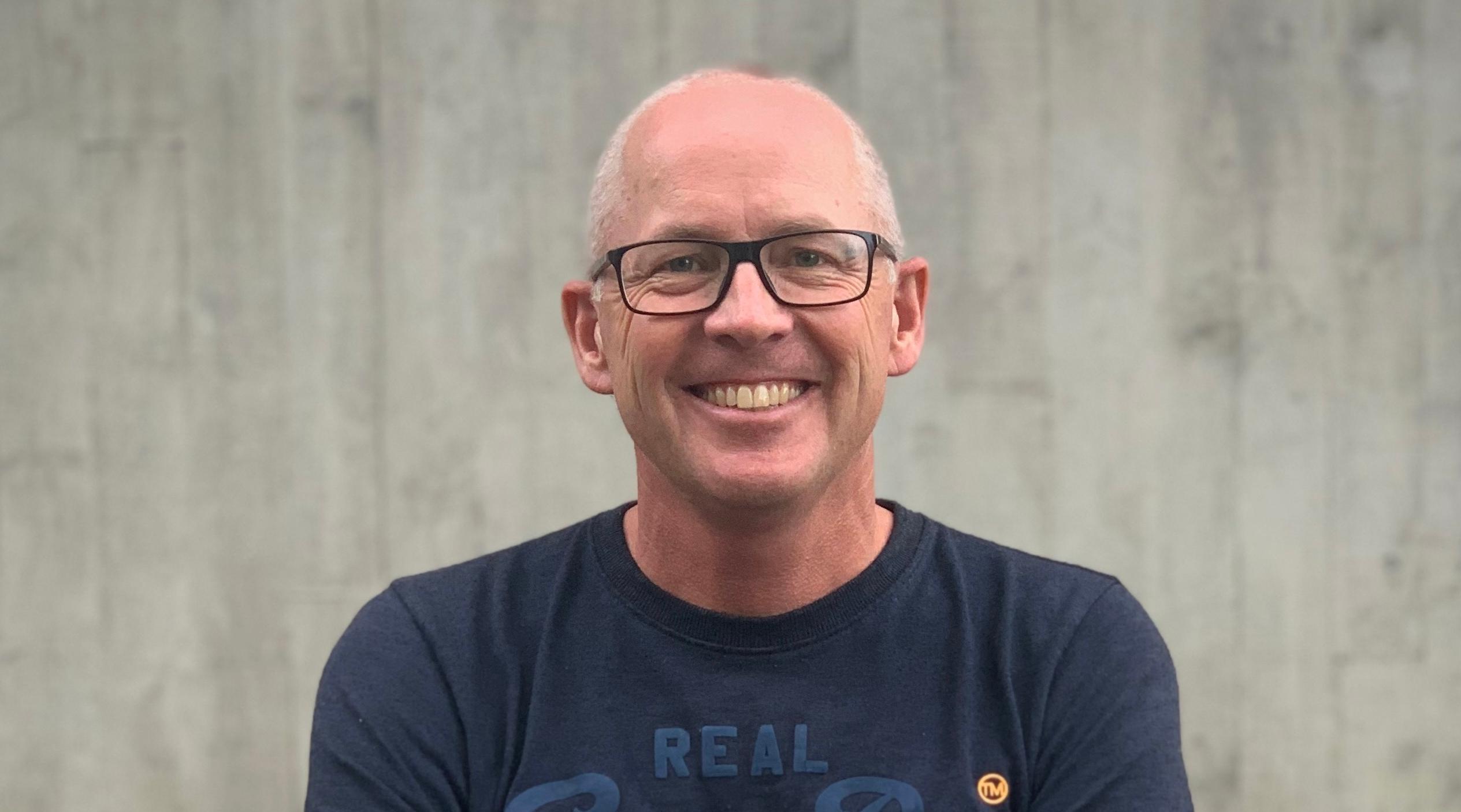 A smiling man with glasses and short grey hair