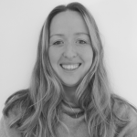 Young white woman with long fair hair and jumper smiling at the camera.