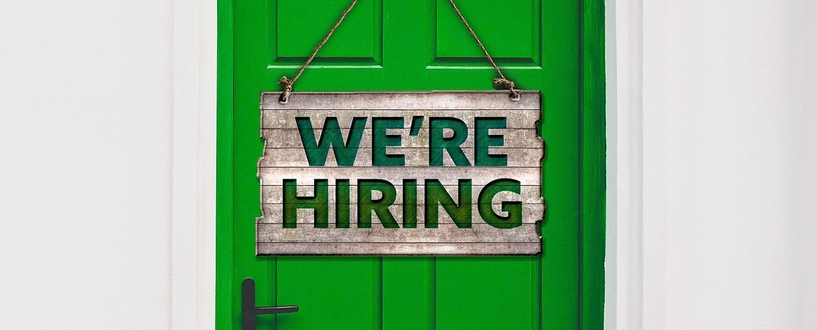 Green wooden door with a sign that reads 'We're hiring'.