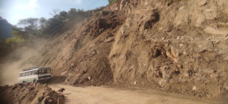 A bus navigating the Rocky Roads of Nepal, where rock partially covers the road