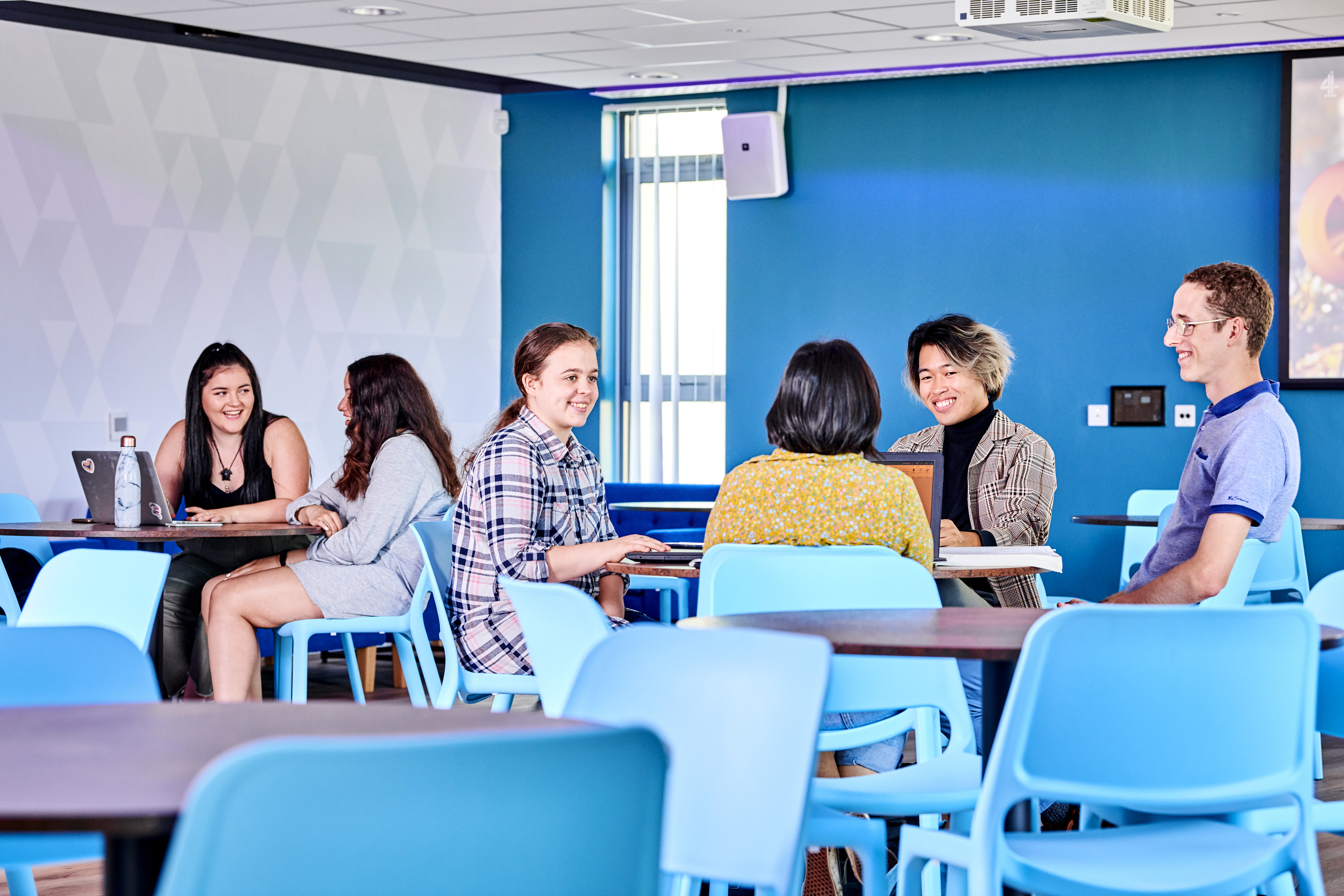 Students socialising at tables in South College social space