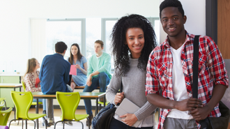 Two students in a social area with others in the background