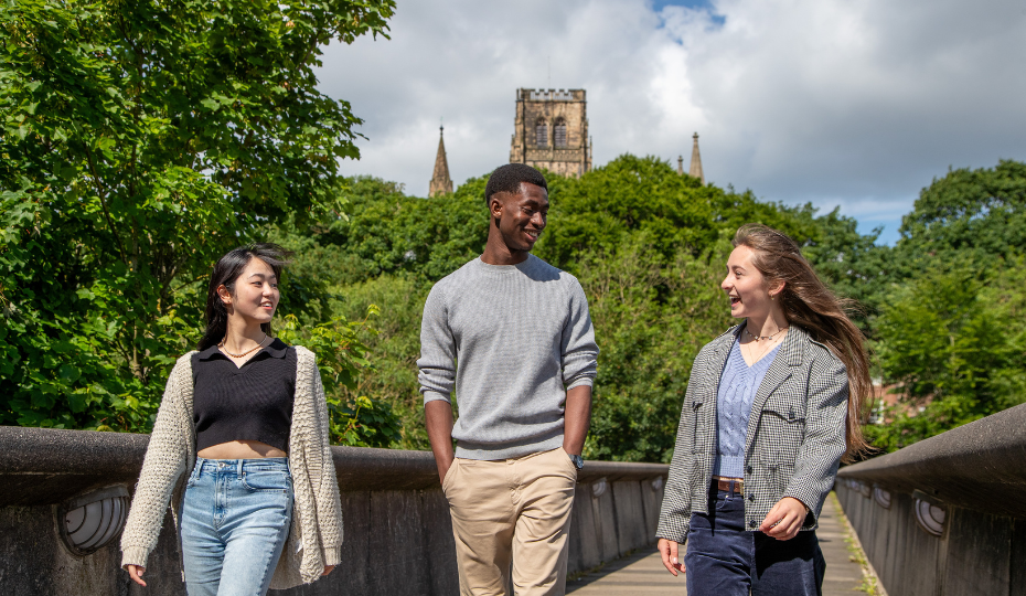 Three students walking across a bridge
