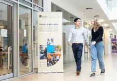 Two students (one male, one female) walking past the Careers and Enterprise banner in the Palatine Centre.