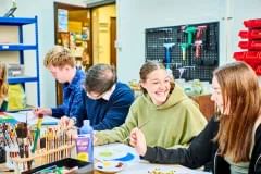 Four students sitting at a table doing art activities