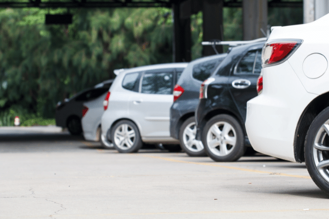 A line of car rears in a carpark with a white car rear in the foreground