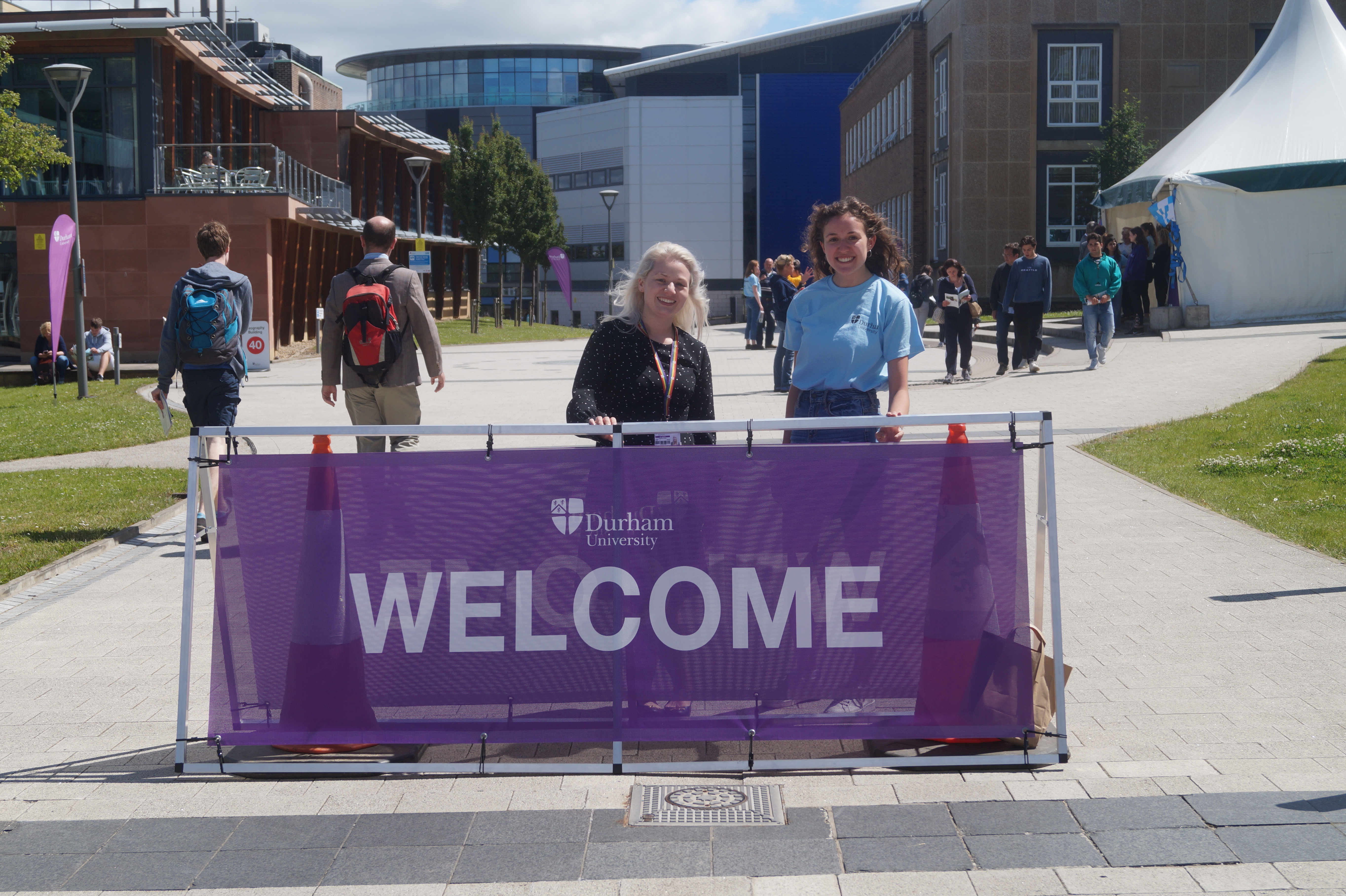 A member of staff and an Open Day Ambassador behind a welcome sign