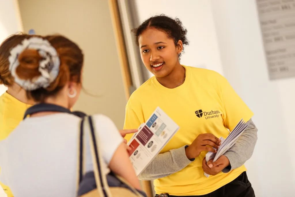 Student ambassador in yellow t-shirt talking to prospective students