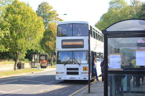 An image of a double decker bus pulling up to a bus stop