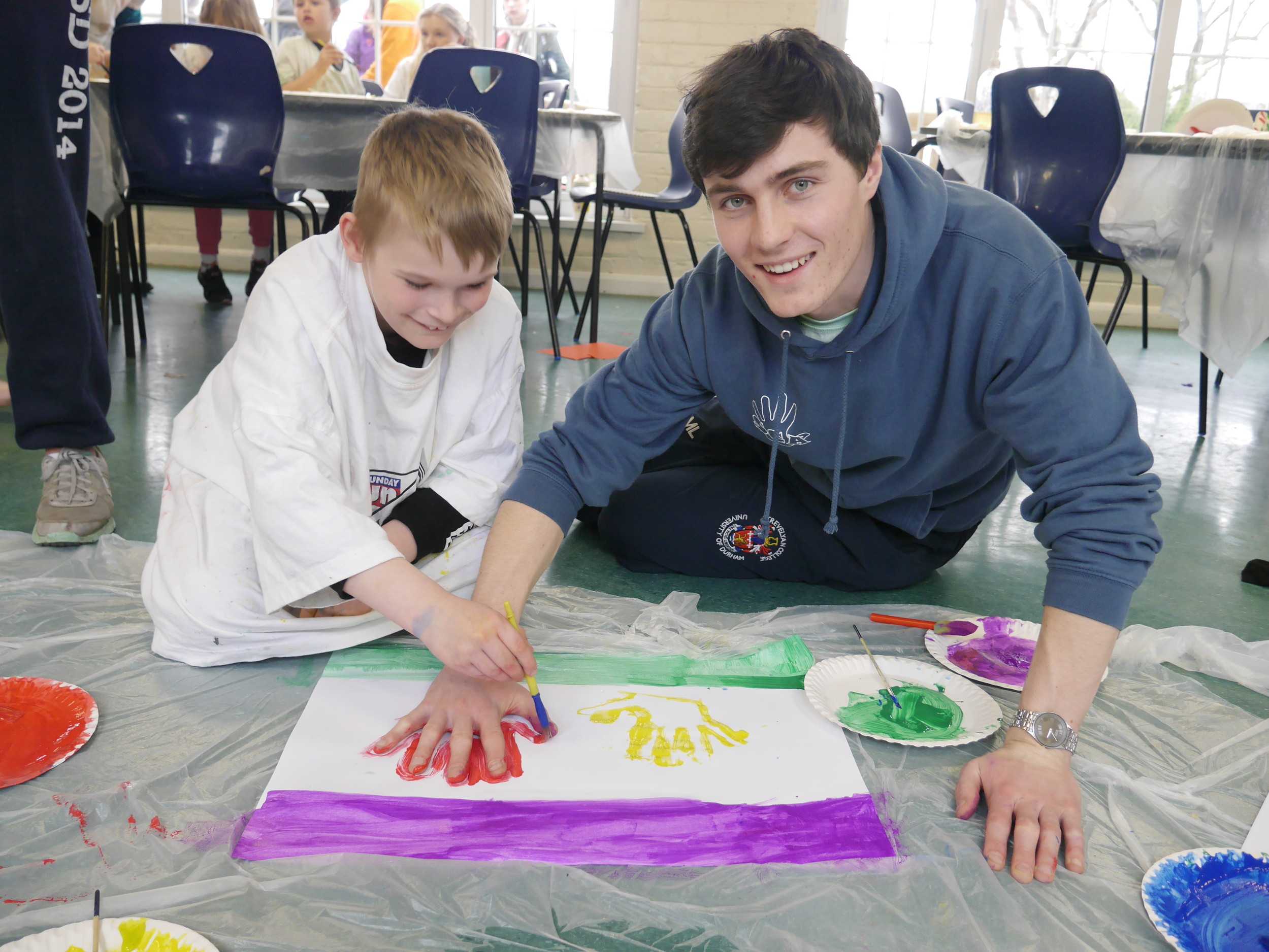 Student hand painting with a child