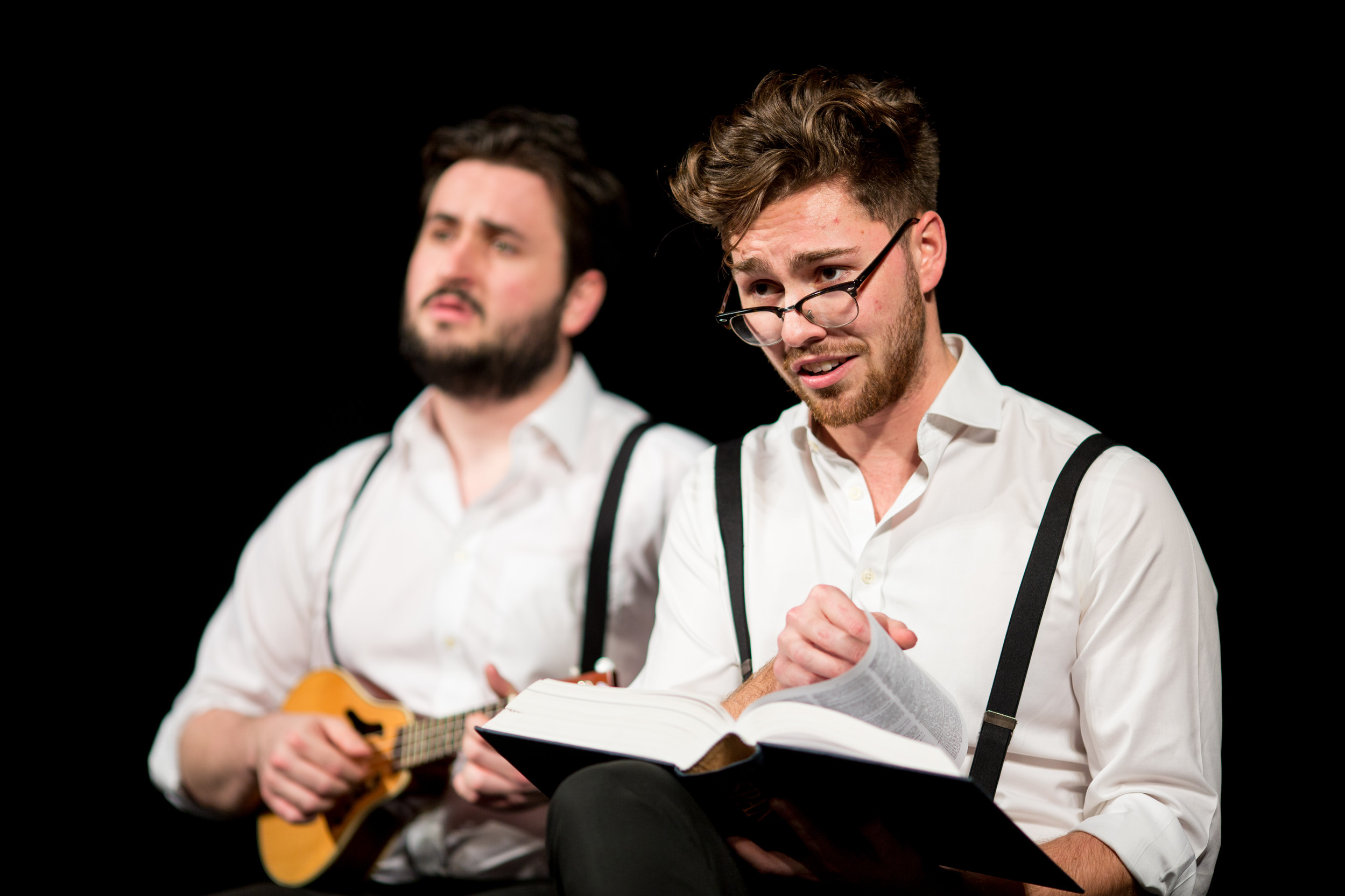 Two actors reading from a book and playing the mandolin