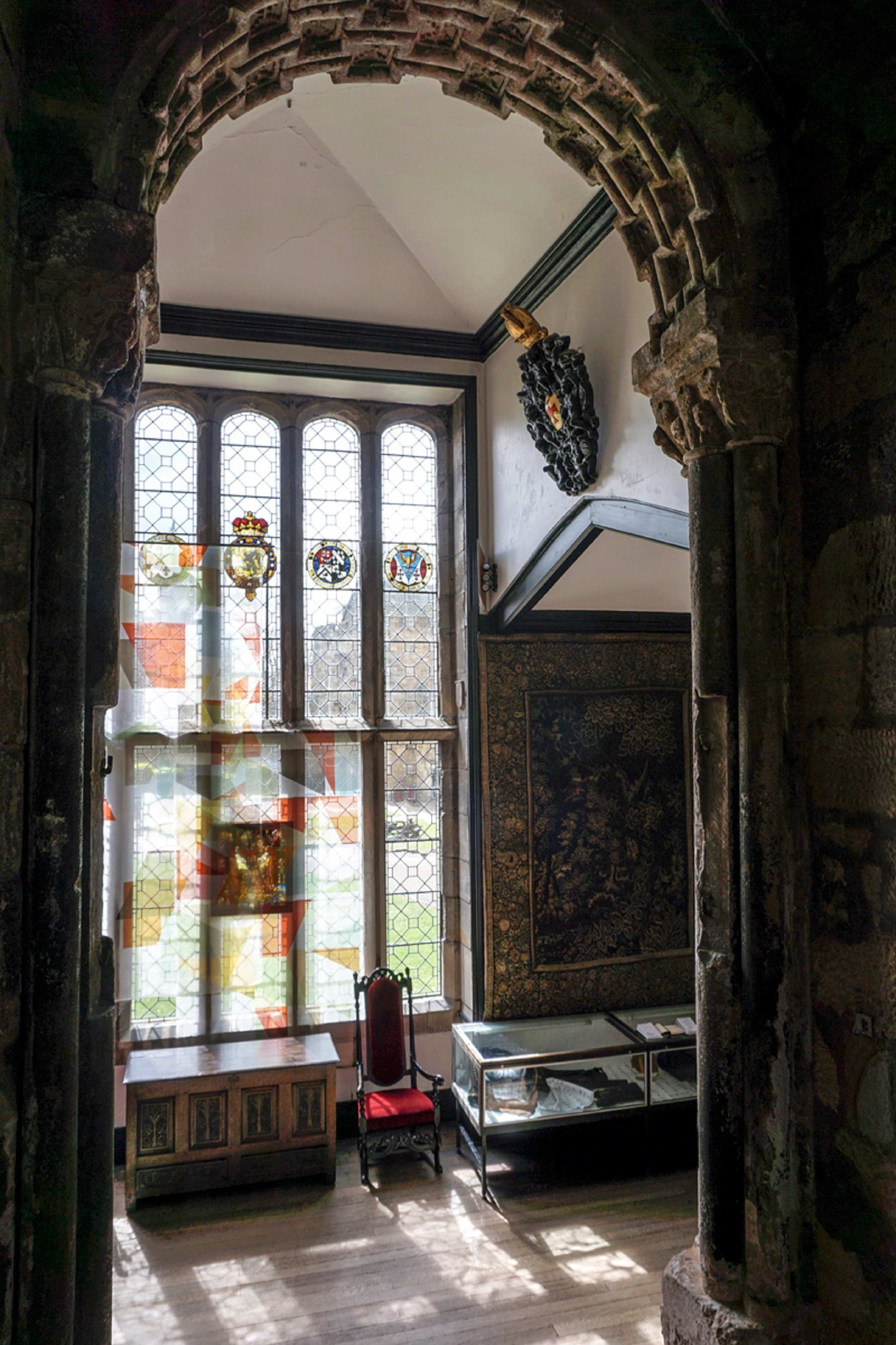 Looking through the Norman Arch, the artwork is on the window and features geometric patterns broken up and made from colours from the bishops' coats of arms and the design theory of Bruno Munari.