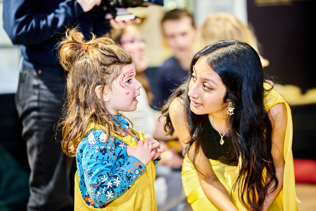 A student and a child talking at Holi event dancing