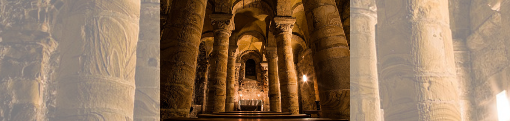 Photograph of the interior of the Norman Chapel at Durham Castle, lit at night by candle-effect lights.