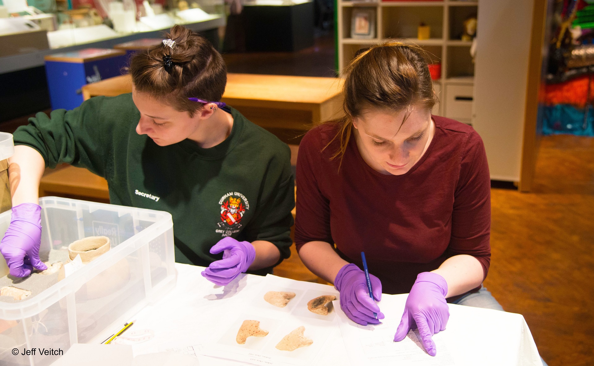 Photograph of two students installing the Shattering Perceptions exhibition