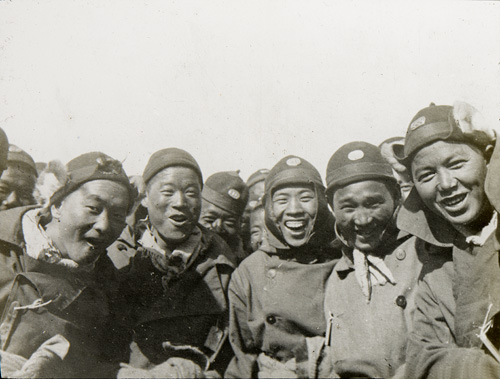 Group of men from the Chinese Labour Corps crowd round for a photograph laughing and smiling.