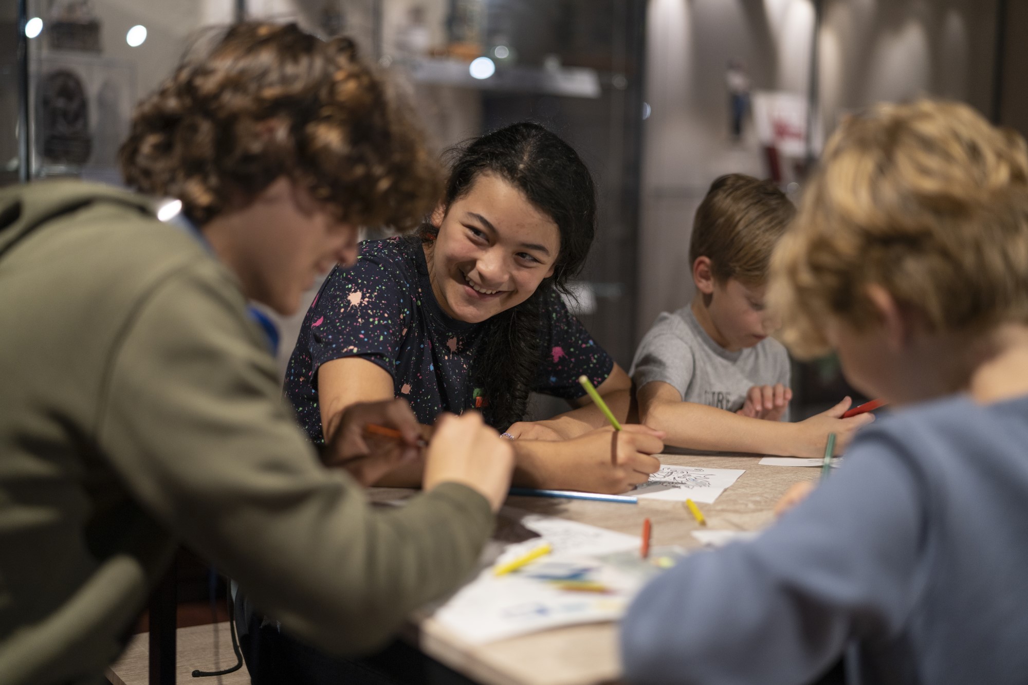 Children sitting at a table and smiling during an event